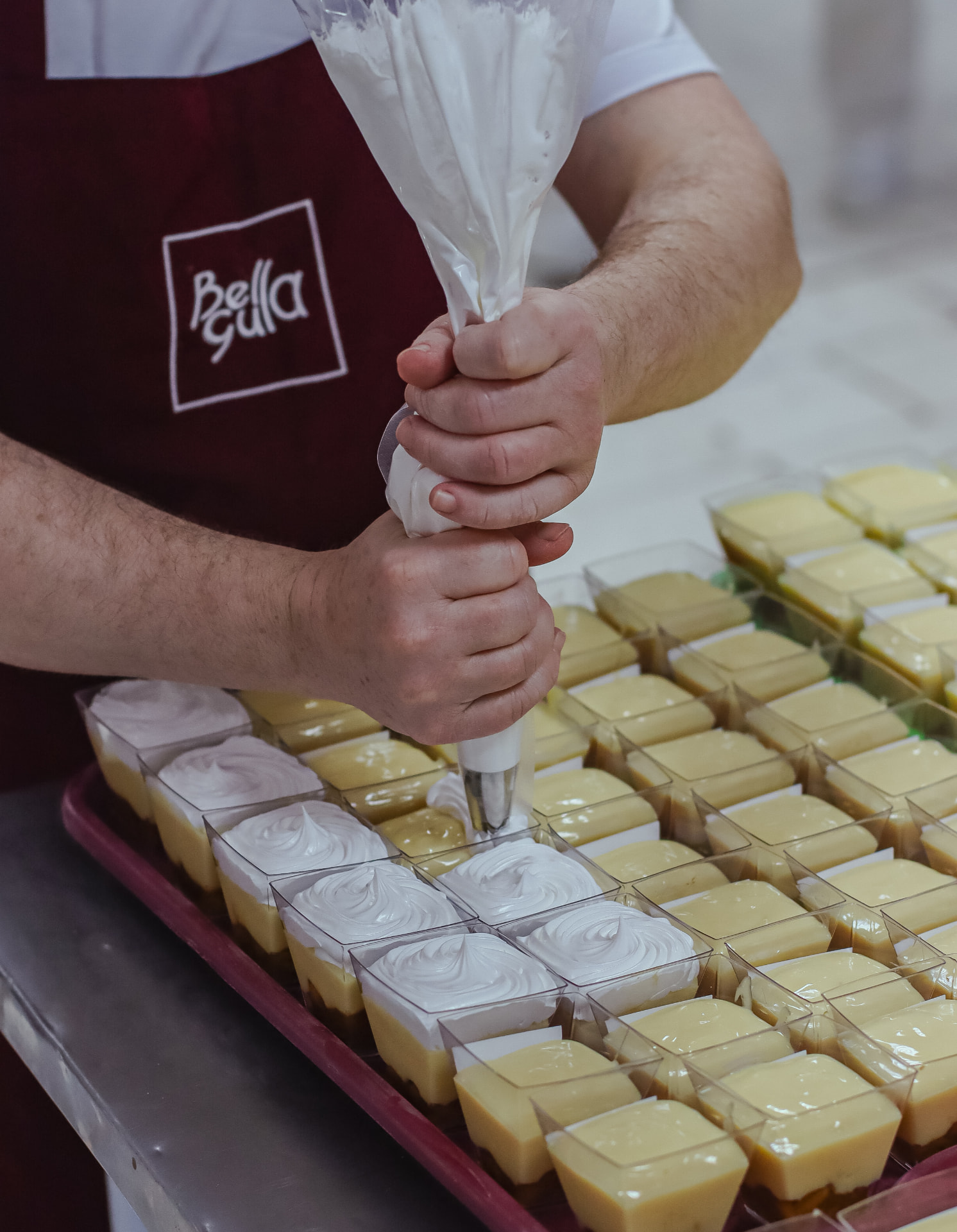Mãos confeitando mini sobremesas na fábrica